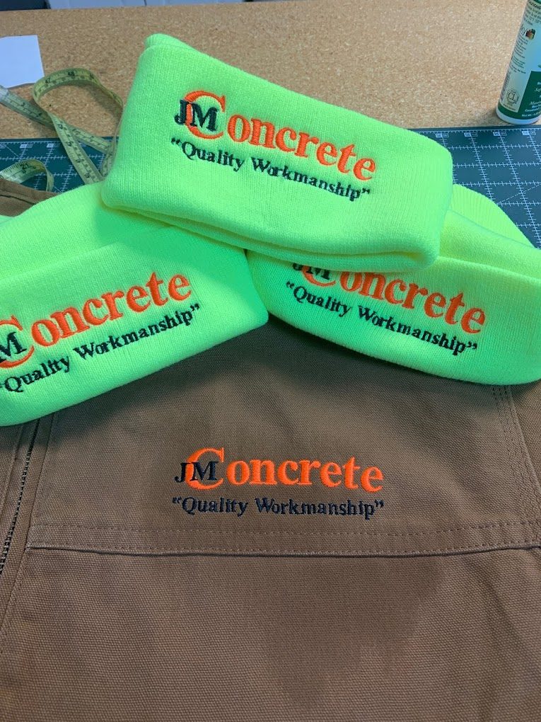 Green beanies, khaki work shirt and caps embroidered with the JM Concrete logo