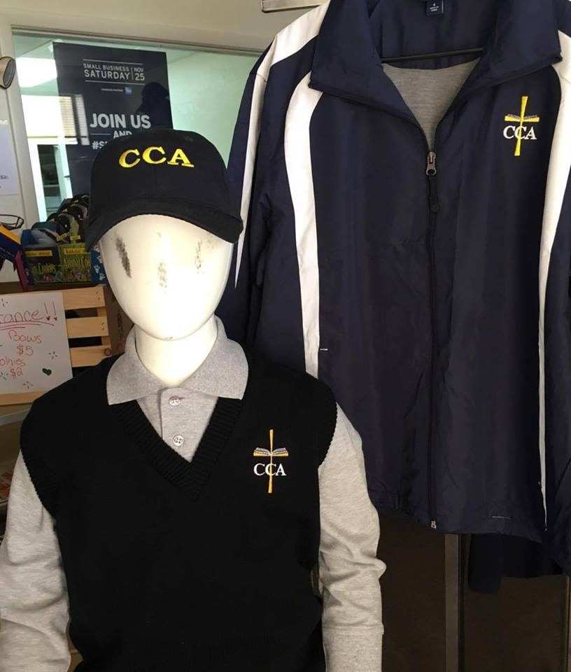 Calvary Chapel Academy uniform display with an embroidered cap, sweater vest, polo and navy jacket